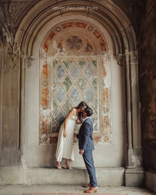 A couple sharing a kiss beneath an ornate stone arch