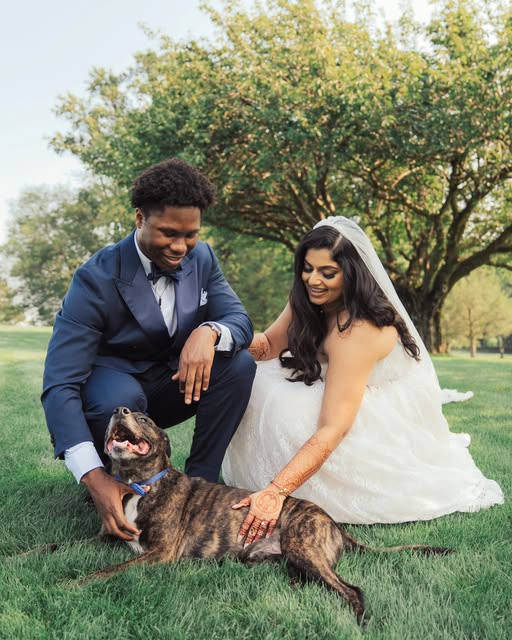 A wedding couple together outdoors with their dog
