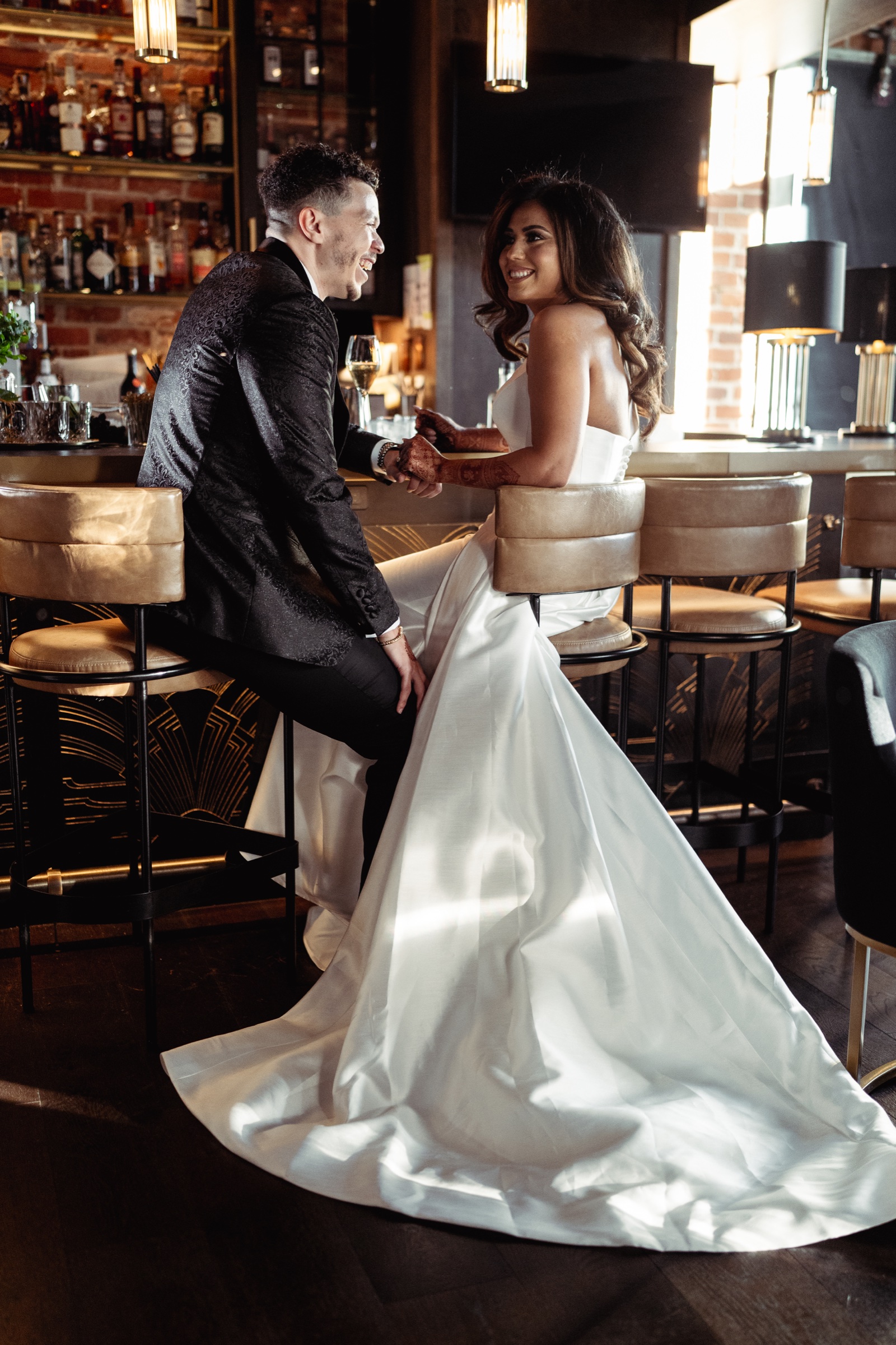 A wedding couple sharing a candid moment in a warmly lit bar